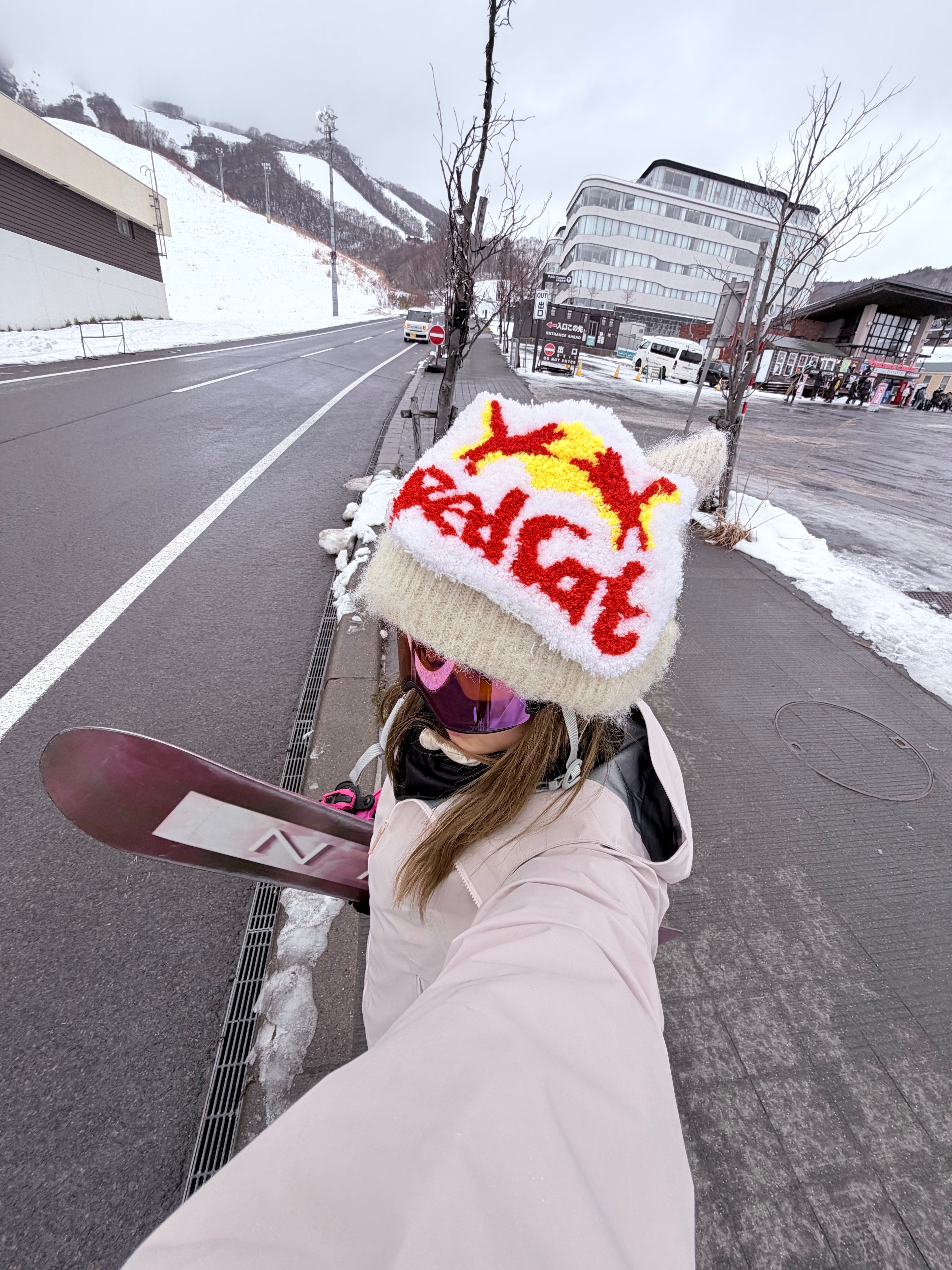 HB Snowear Cat-Ear Mohair Ski Beanie Beige — lifestyle shot with snowboard at ski resort